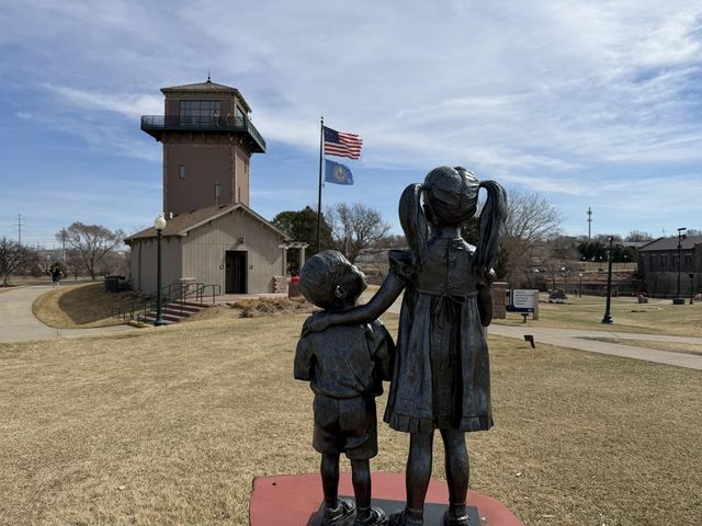 The Falls Park viewing tower behind a bronze statue of a girl and her brother