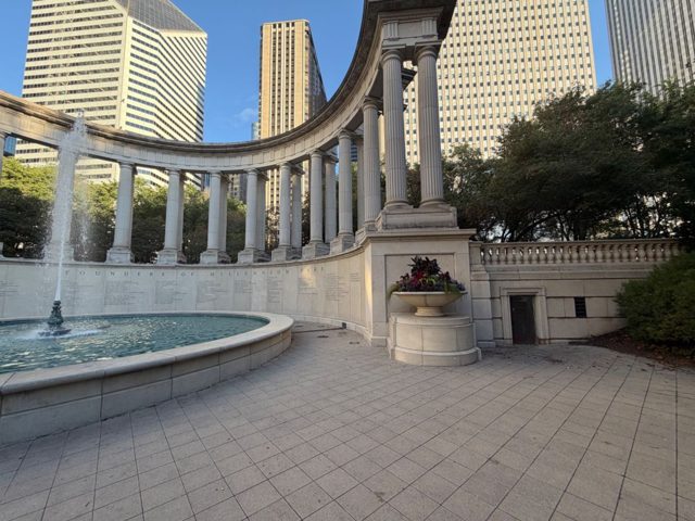 A curved row of white columns around a fountain at Wrigley Square