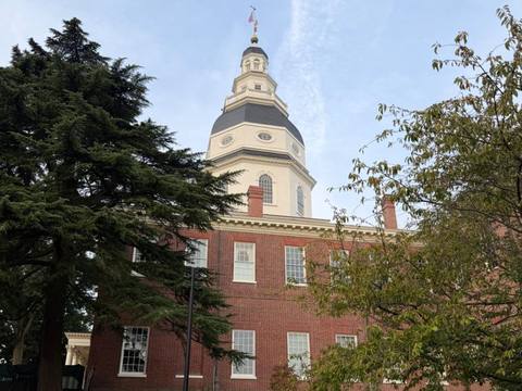 The Maryland State House dome above red brick walls and trees