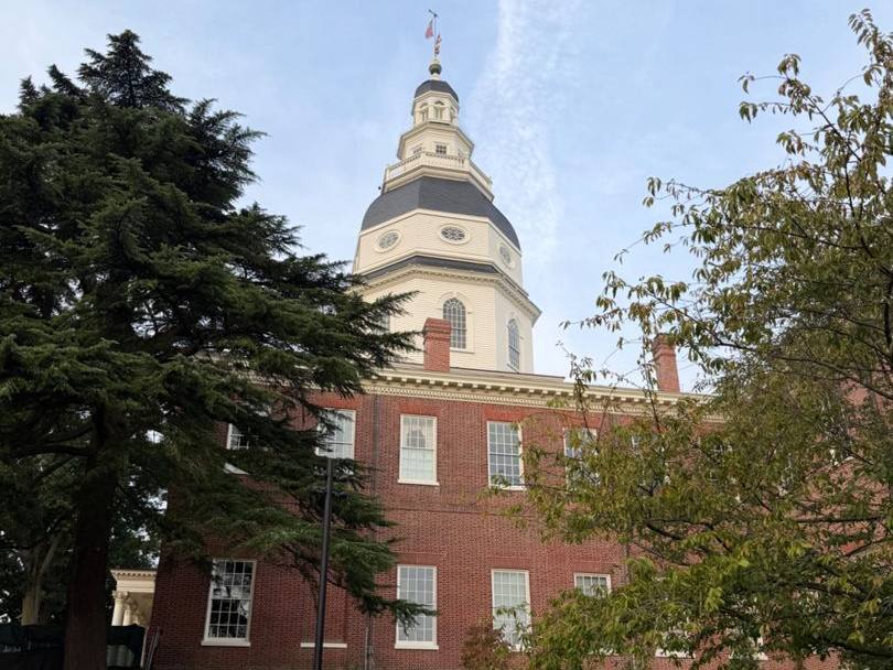 The Maryland State House dome above red brick walls and trees